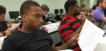 Several college-aged students work together in a mathematics classroom. 