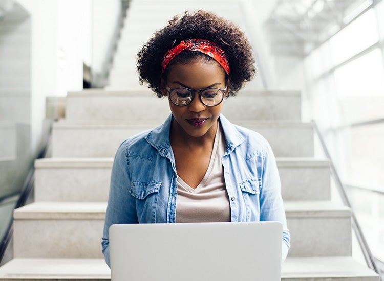 woman working on laptop sitting on stairs