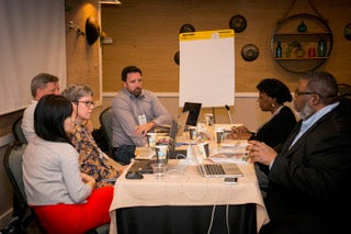 six participants in a professional learning session around a chart paper