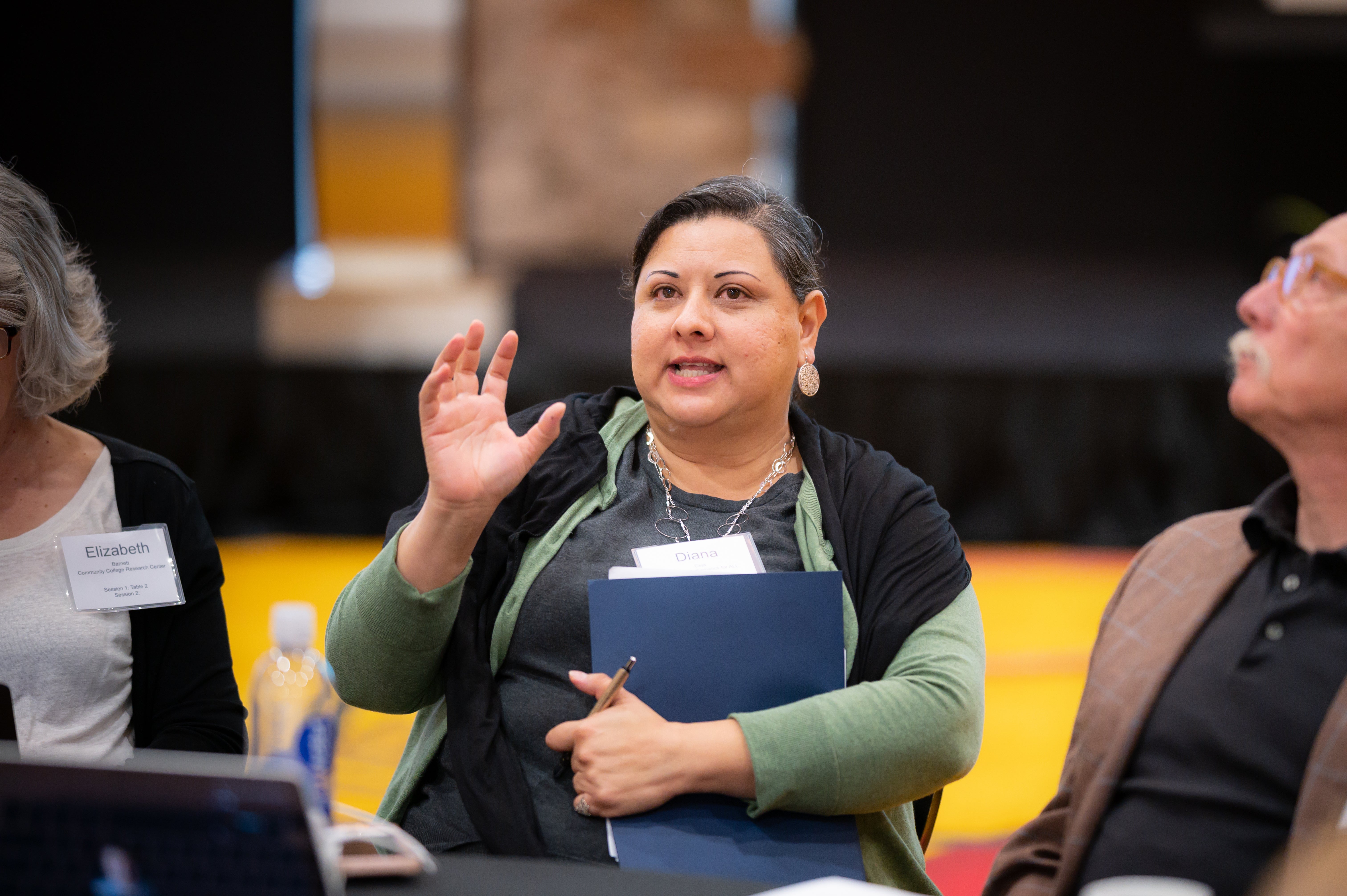 three people seated with one woman speaking