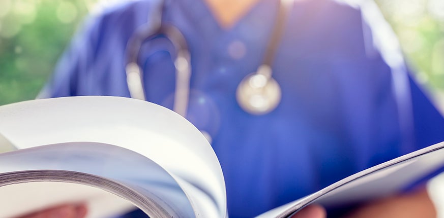 A closeup image of a nurse holding a book.