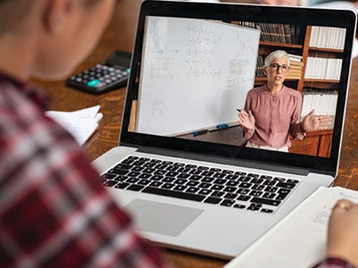 A female professor appears on a student's laptop screen during a lesson.