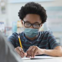 student in facial covering doing school work