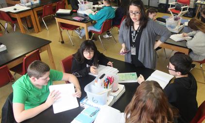 teacher talking with students at a table