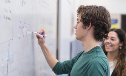 student writing on a whiteboard