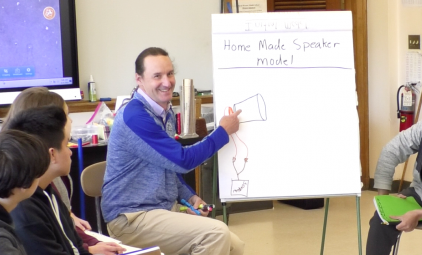 teacher chris newlan shows student diagram for making a home made speaker