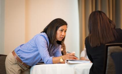 Denise Thornton leaning on a table while listening to someone.