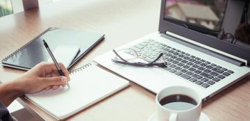 person working with laptop and notebook