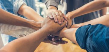 A group of people joining hands.