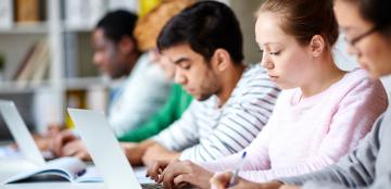 Students studying using laptops and books.