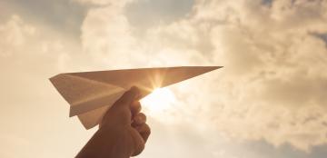 Paper airplane held in a child's hand.