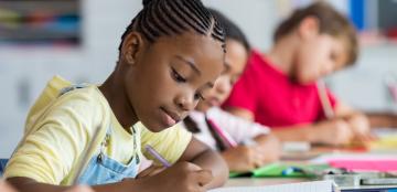 Young girls writing in a notebook.