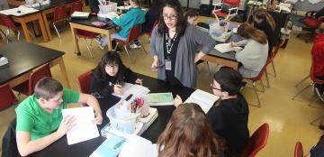 teacher talking with students at a table