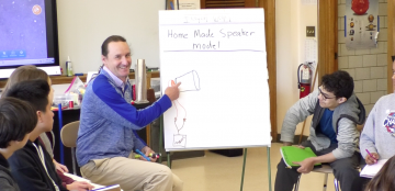 teacher chris newlan shows student diagram for making a home made speaker
