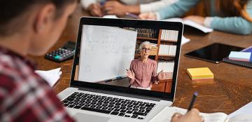 A student watches on his computer as an instructor presents a virtual lesson.