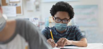 student in facial covering doing school work