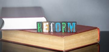 the word "reform" spelled out in blocks on top of books