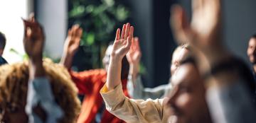 group of students raising their hands to answer a question