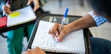 close up of college student doing math work in a spiral notebook