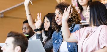 Students in a lecture hall raising their hands