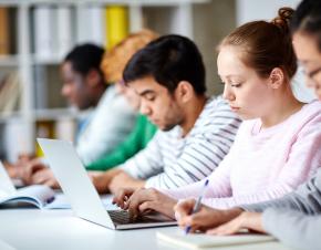 Students studying using laptops and books.