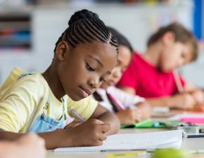 Young girls writing in a notebook.