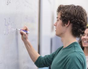 student writing on a whiteboard