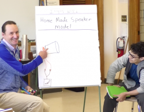 teacher chris newlan shows student diagram for making a home made speaker