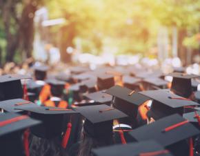 students in graduation caps and gowns outside