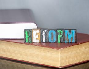 the word "reform" spelled out in blocks on top of books