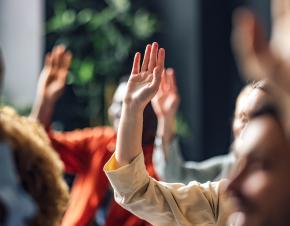 group of students raising their hands to answer a question