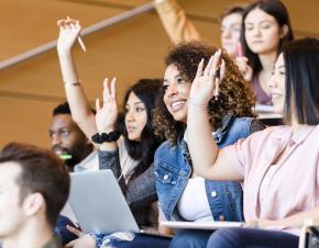 Students in a lecture hall raising their hands