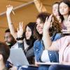 Students in a lecture hall raising their hands